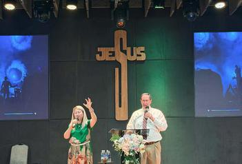 Pastors Bill and Jennifer Marshall ministering together beneath a cross